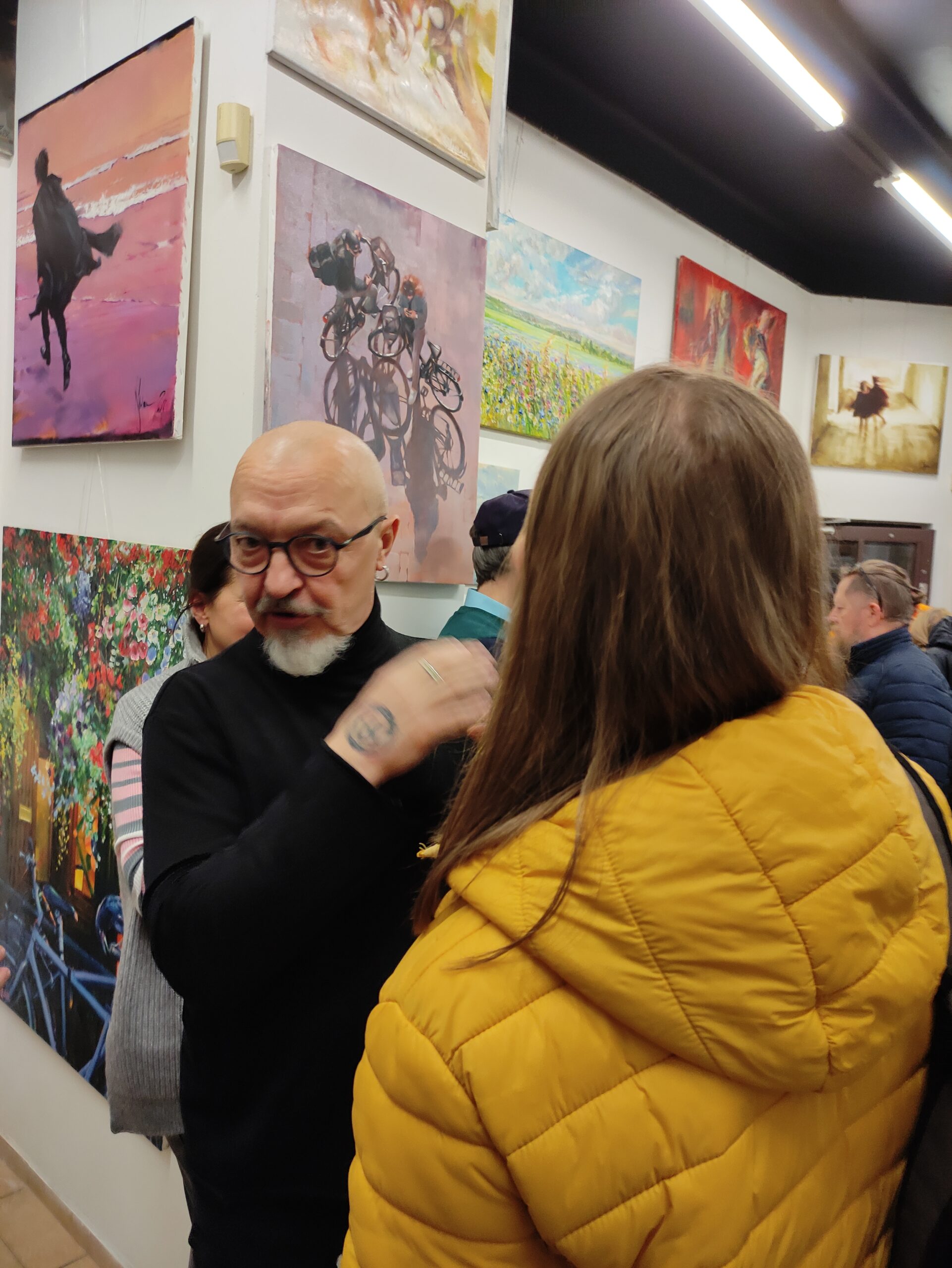 
Igor Shulman standing among guests with his paintings displayed at ART Gallery 11 Prague