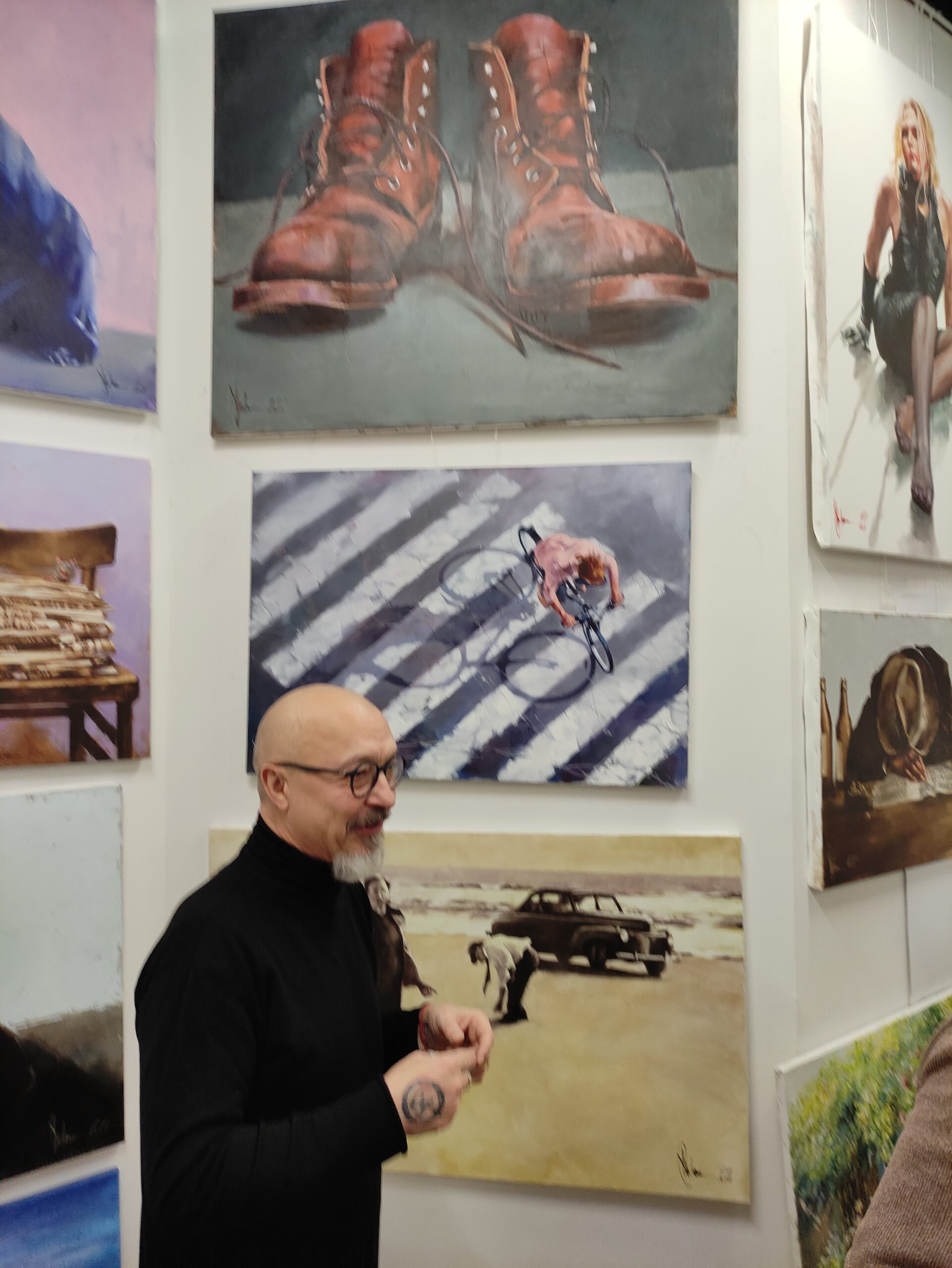 Igor Shulman standing next to his paintings "Just Shoes," "Evening Sketch," and "An Unscheduled Visit to the East Coast" at ART Gallery 11 Prague