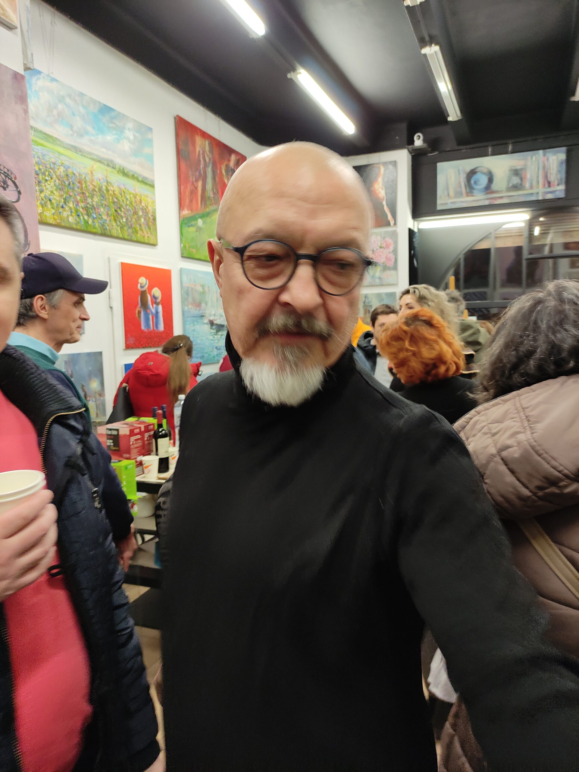 Igor Shulman interacting with visitors surrounded by his paintings at ART Gallery 11 Prague exhibition